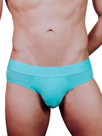 A close-up of a male model's lower torso wearing bright turquoise blue briefs with the brand name 'SUPAWEAR' printed on the front waistband, set against a plain white background.