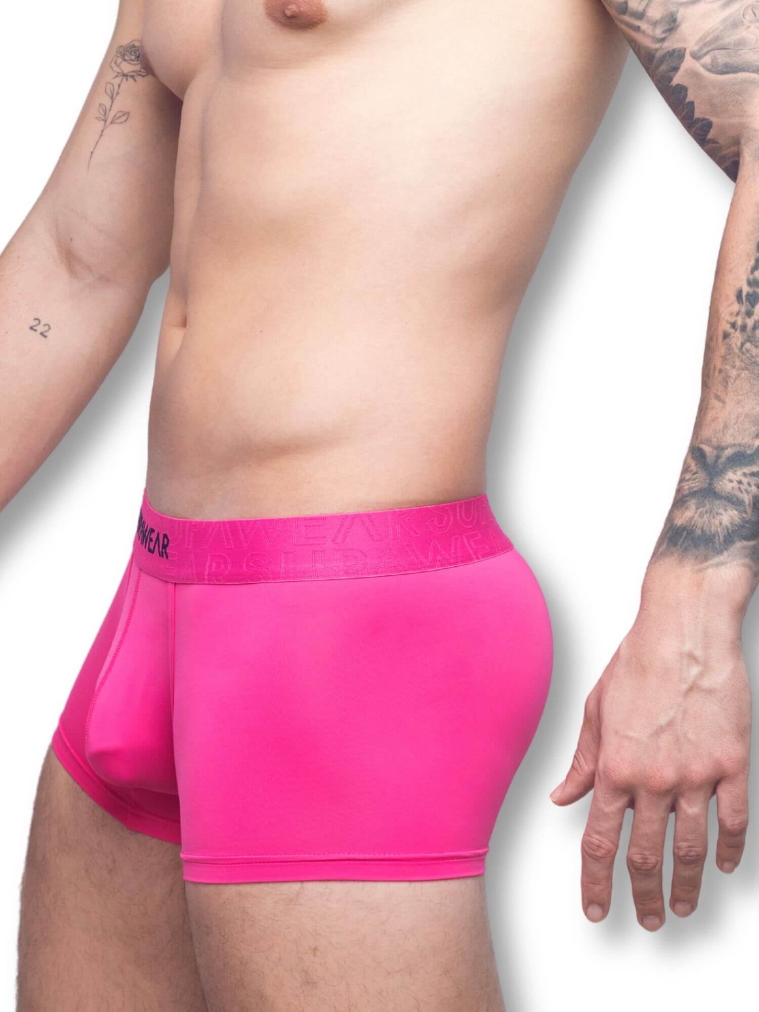 Person wearing bright neon pink boxer briefs on a white background