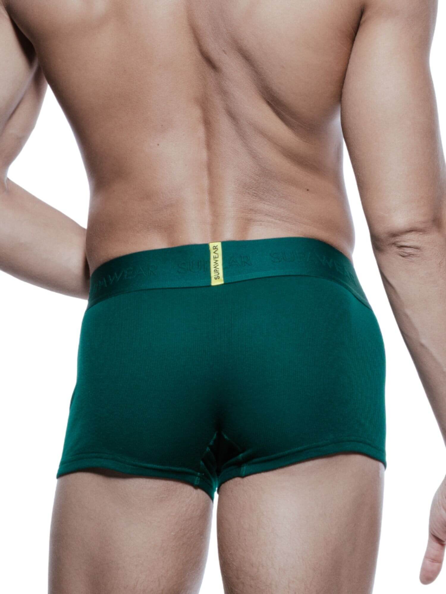 A man shown from the back wearing dark green boxer briefs with a small yellow brand tab at the center of the waistband.
