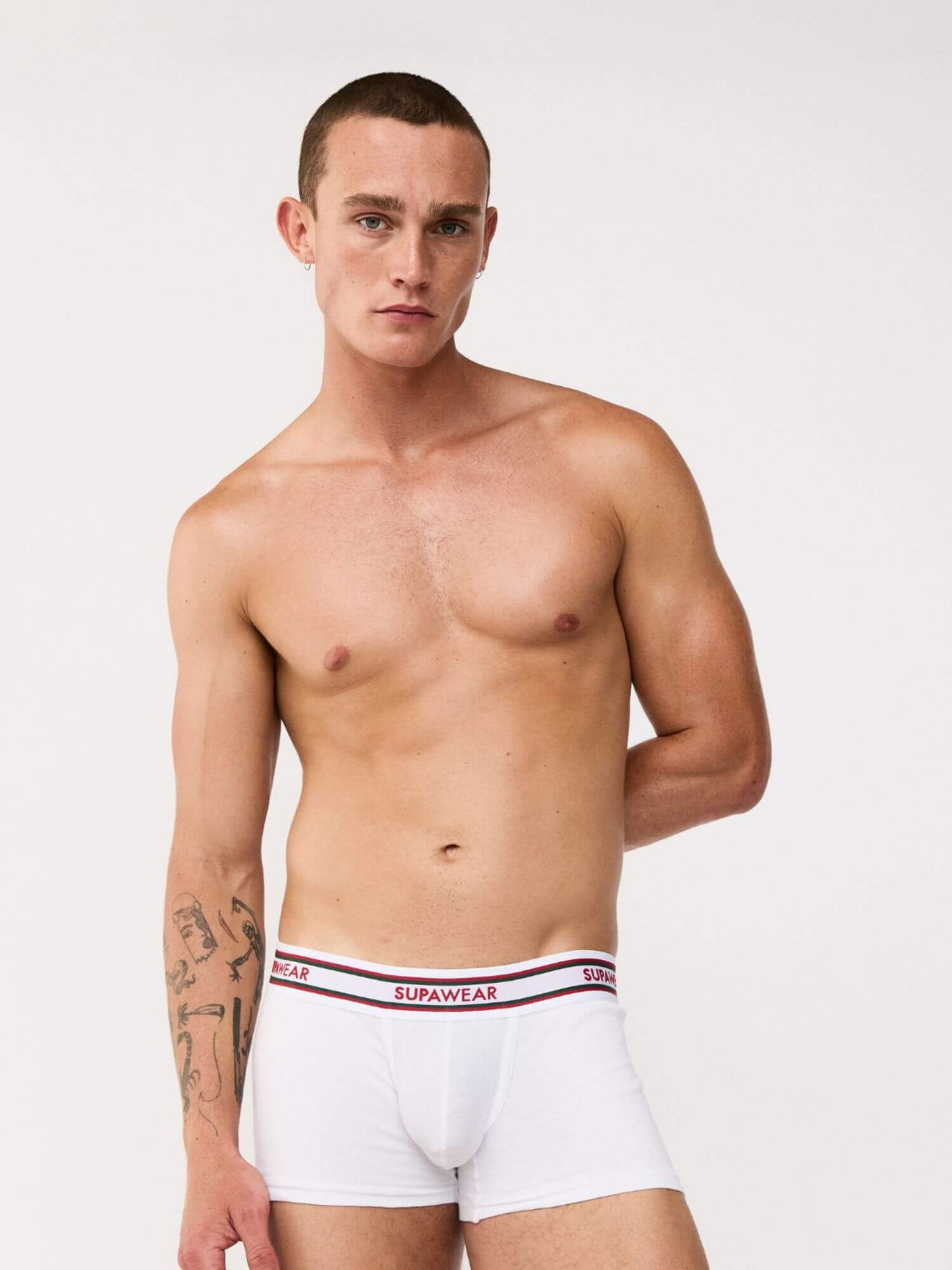 Man wearing white underwear with a visible brand logo on a plain background