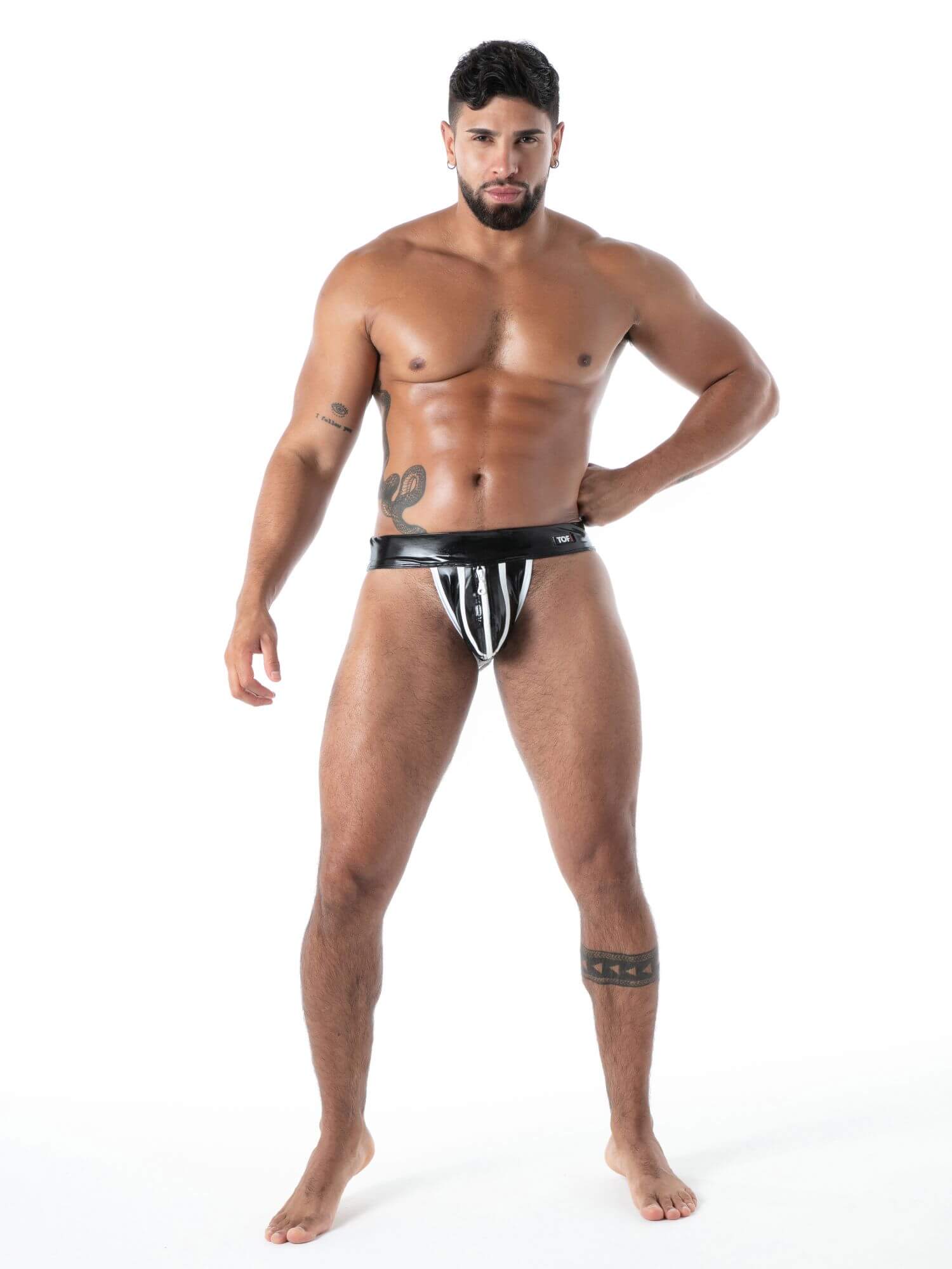 Man wearing a black and white striped latex jockstrap  on a white background