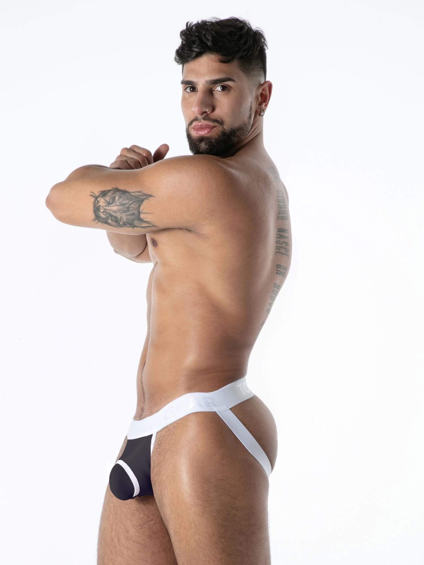 Man wearing a black and white jockstrap against a white background