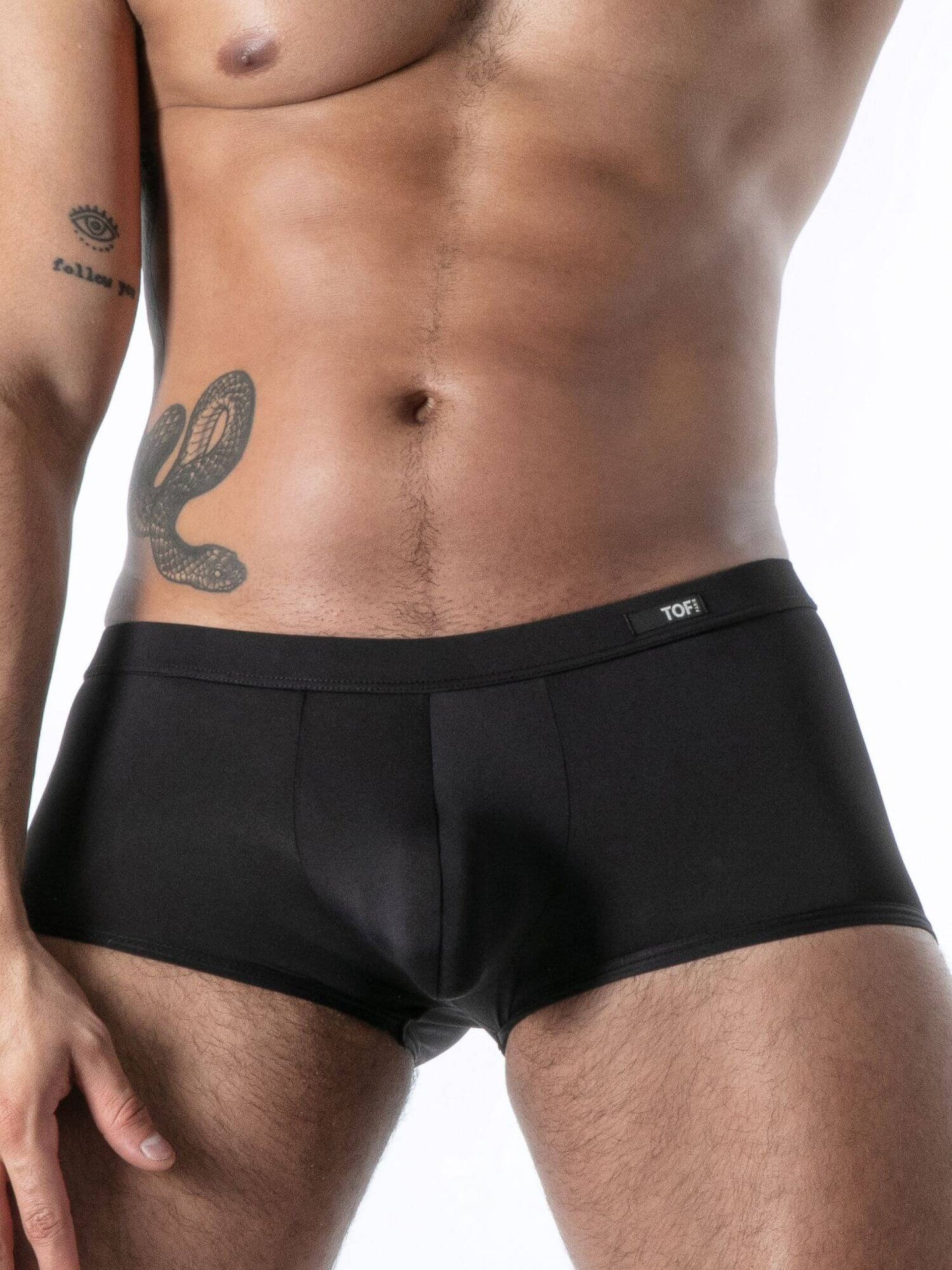 Man wearing black boxer briefs with a visible brand logo on a white background