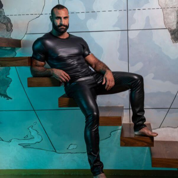 Man in black leather outfit sitting on steps with a map background