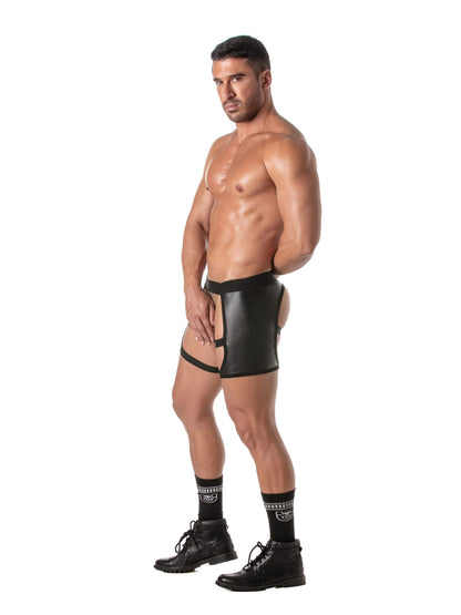 A muscular man modeling black faux-leather briefs with a front cutout and garter straps, paired with black crew socks and black boots, against a solid white background.
