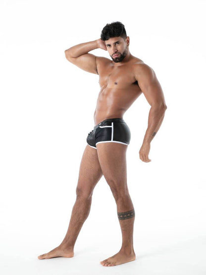 Man wearing black leather look boxer trunks with white trim on a white background