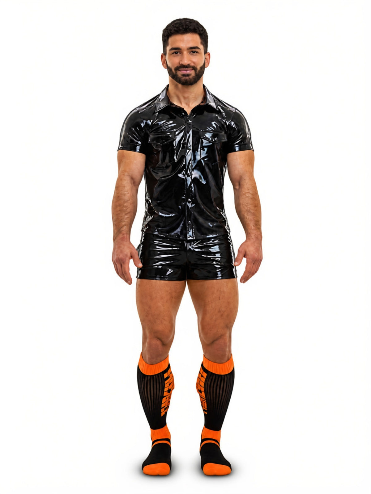 A man modeling a halloween outfit with shiny black vinyl short-sleeve collared shirt and matching black vinyl shorts, paired with black and orange knee-high socks, against a plain white background.