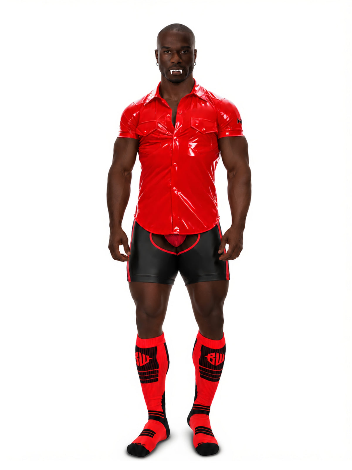 A muscular man modeling a halloween outfit with glossy red short-sleeve button-up shirt, black leather-look shorts, and matching red and black knee-high socks against a plain white background.