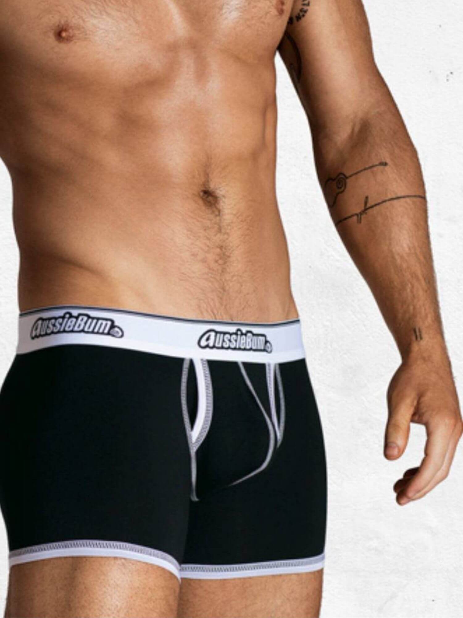 Person wearing black underwear with white waistband featuring 'AussieBum' brand on a plain background.
