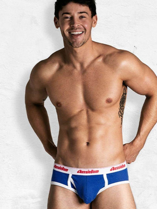 Man wearing blue and white underwear with red accents on a plain background