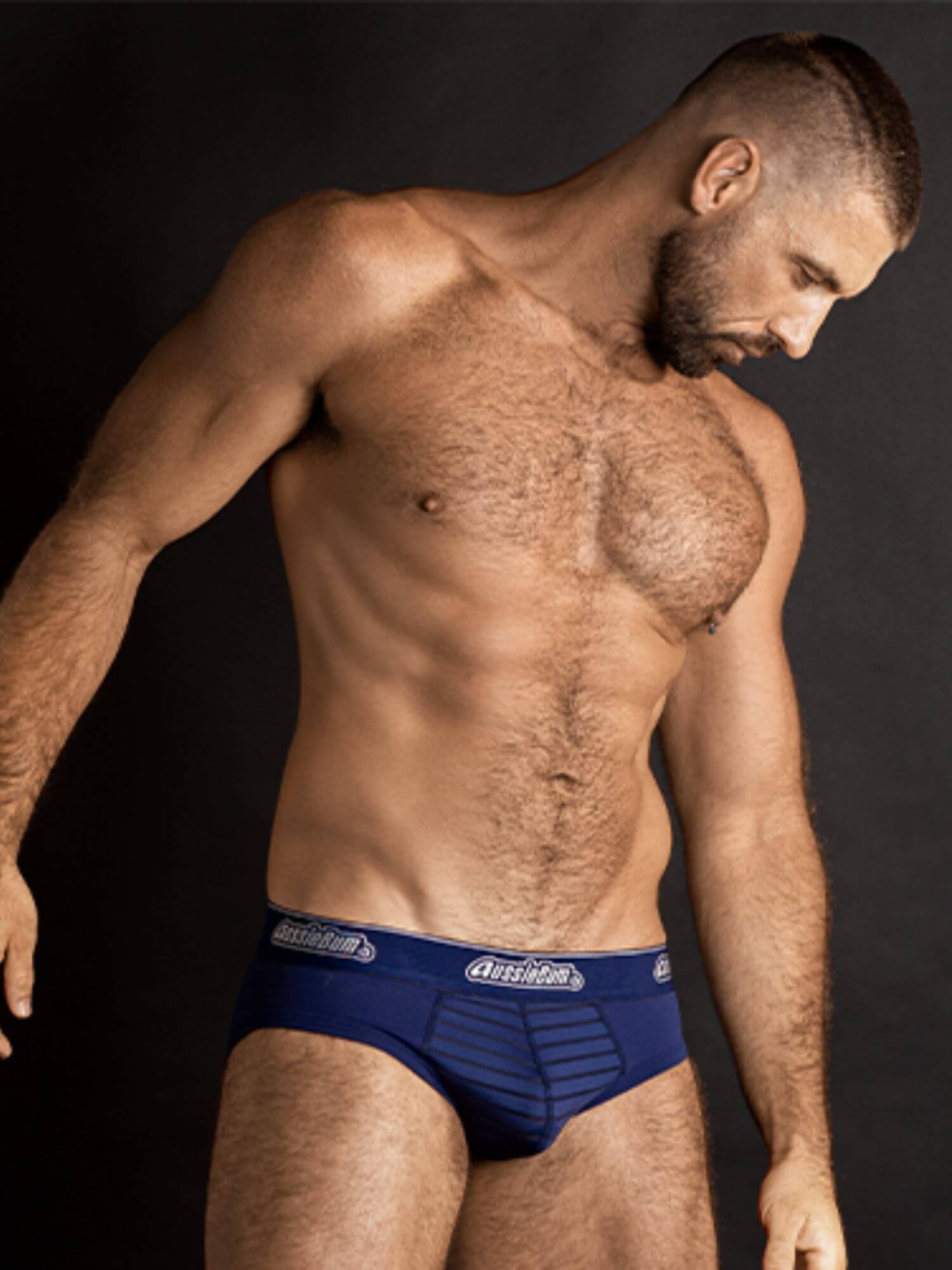Man wearing blue underwear with a brand logo on a black background