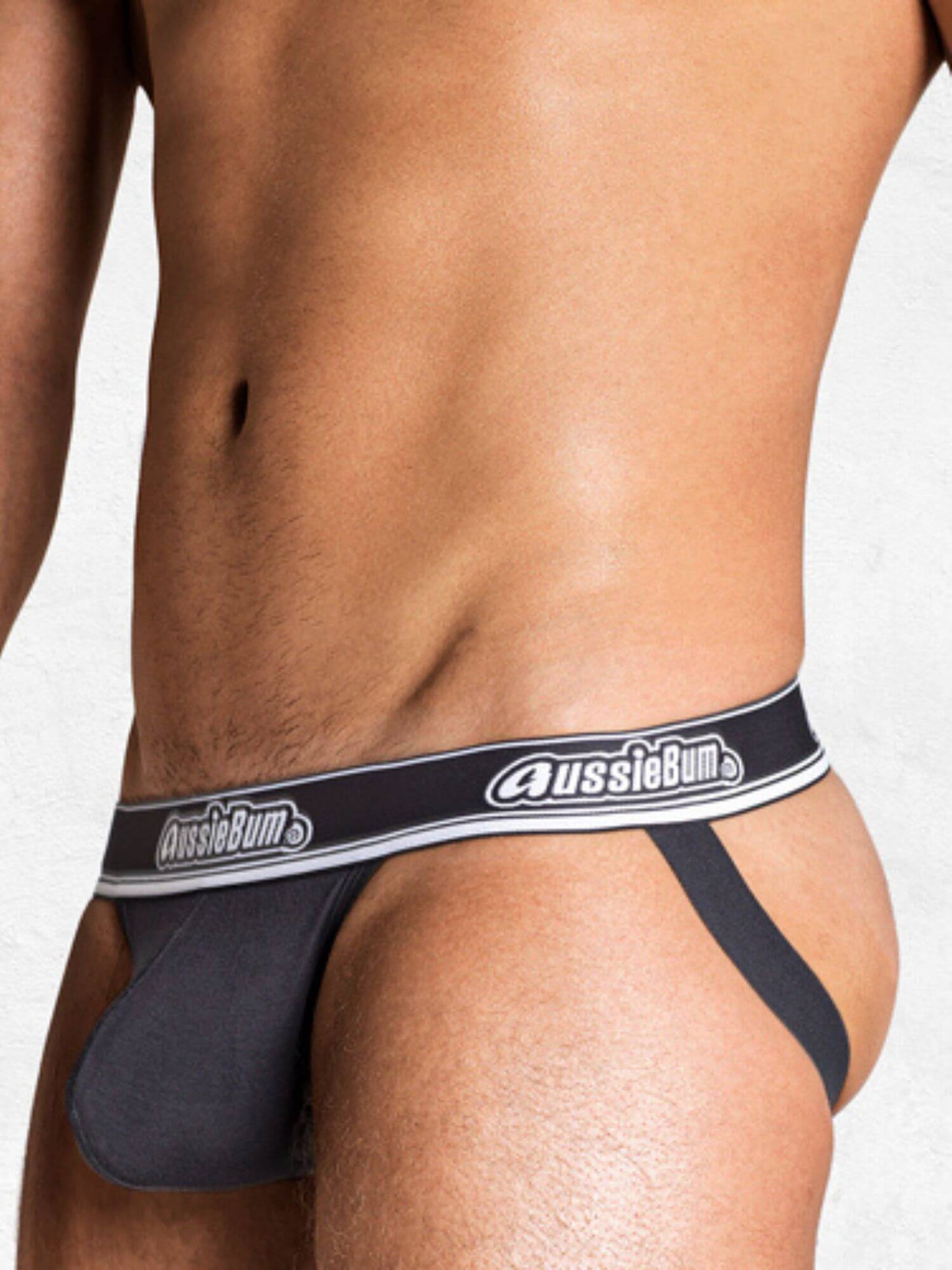 Person wearing a grey jockstrap with 'AussieBum' branding on a plain background