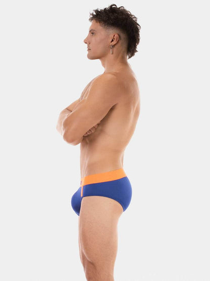 Person wearing blue and orange swim briefs on a white background