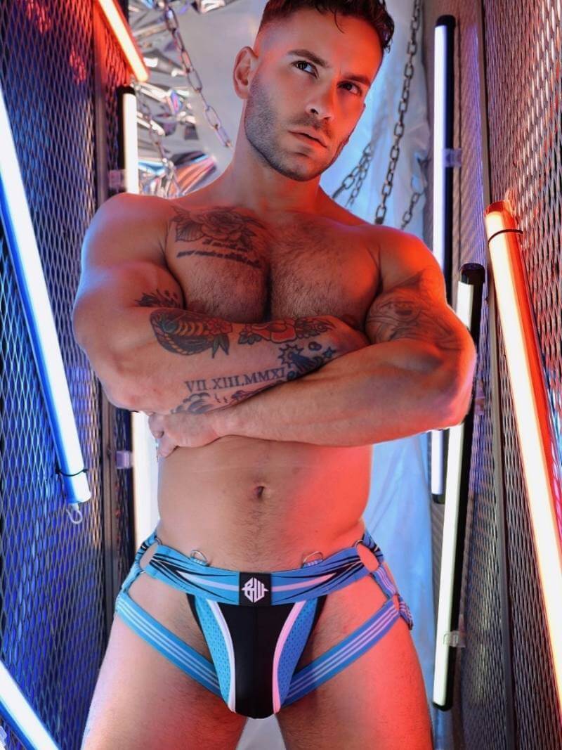 Man wearing colorful underwear with tattoos on a vibrant background