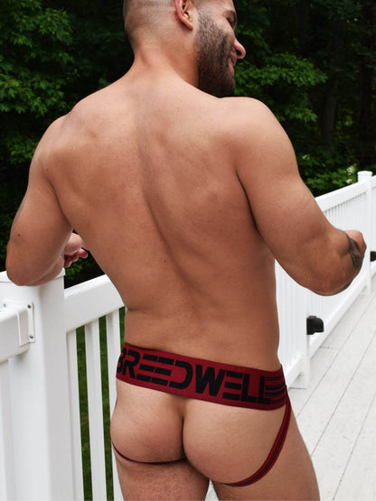 man wearing breedwell red cumdump athletic clubwear jockstrap with large letter branding