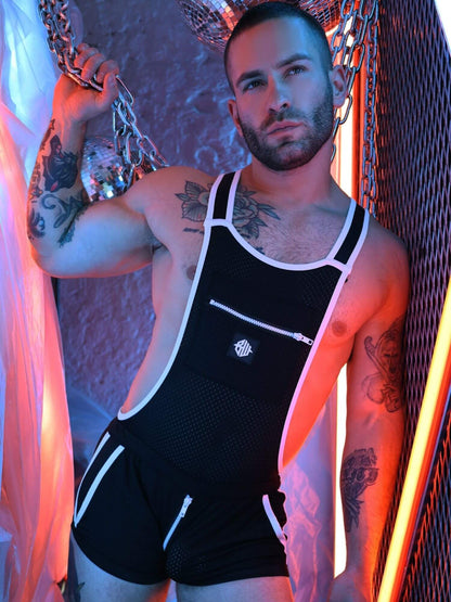 Man wearing a black overalls with white trim in a colorful, abstract setting