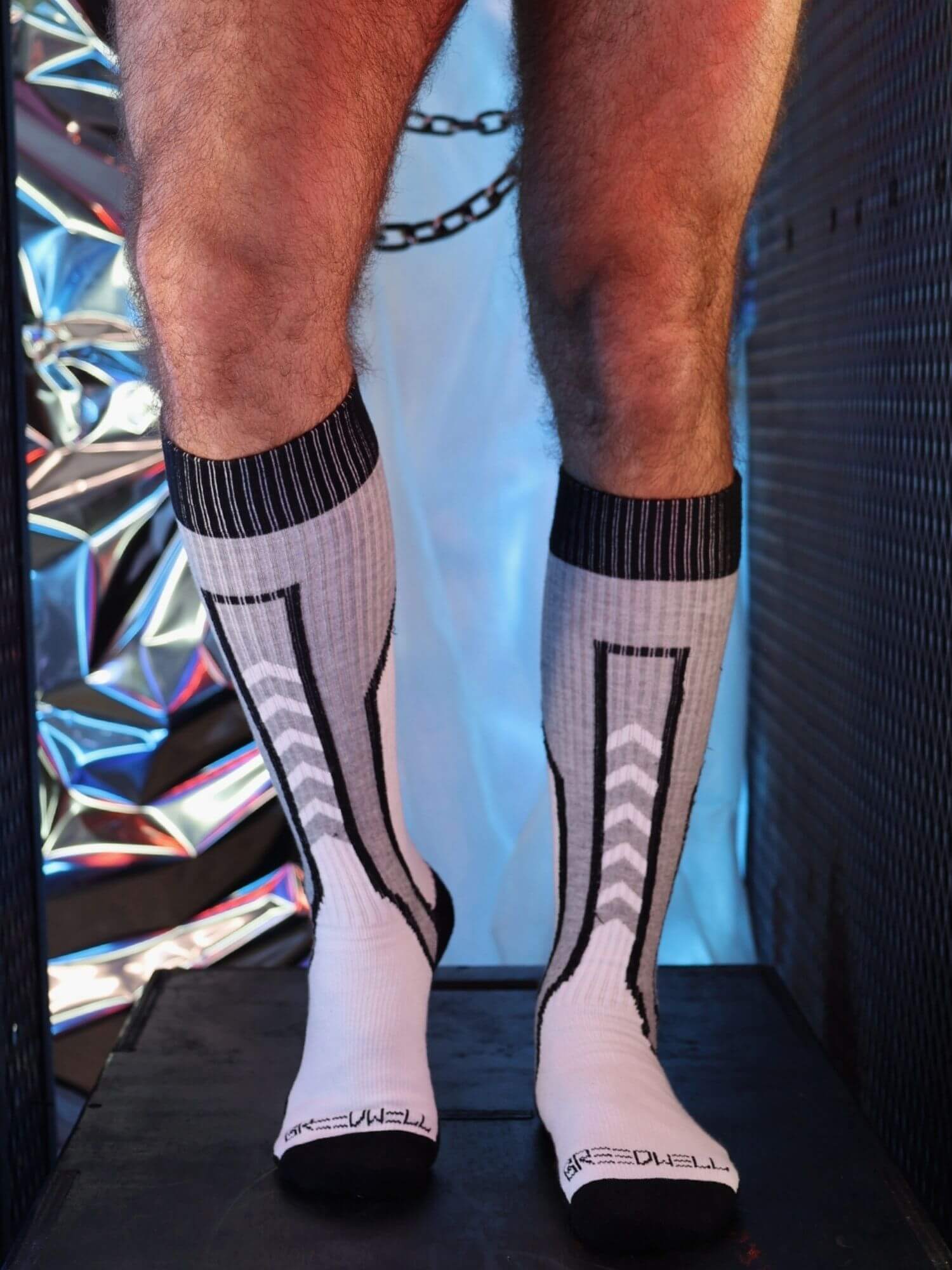 White socks with black patterns worn by a person against a colorful, reflective background.
