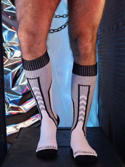 White socks with black patterns worn by a person against a colorful, reflective background.