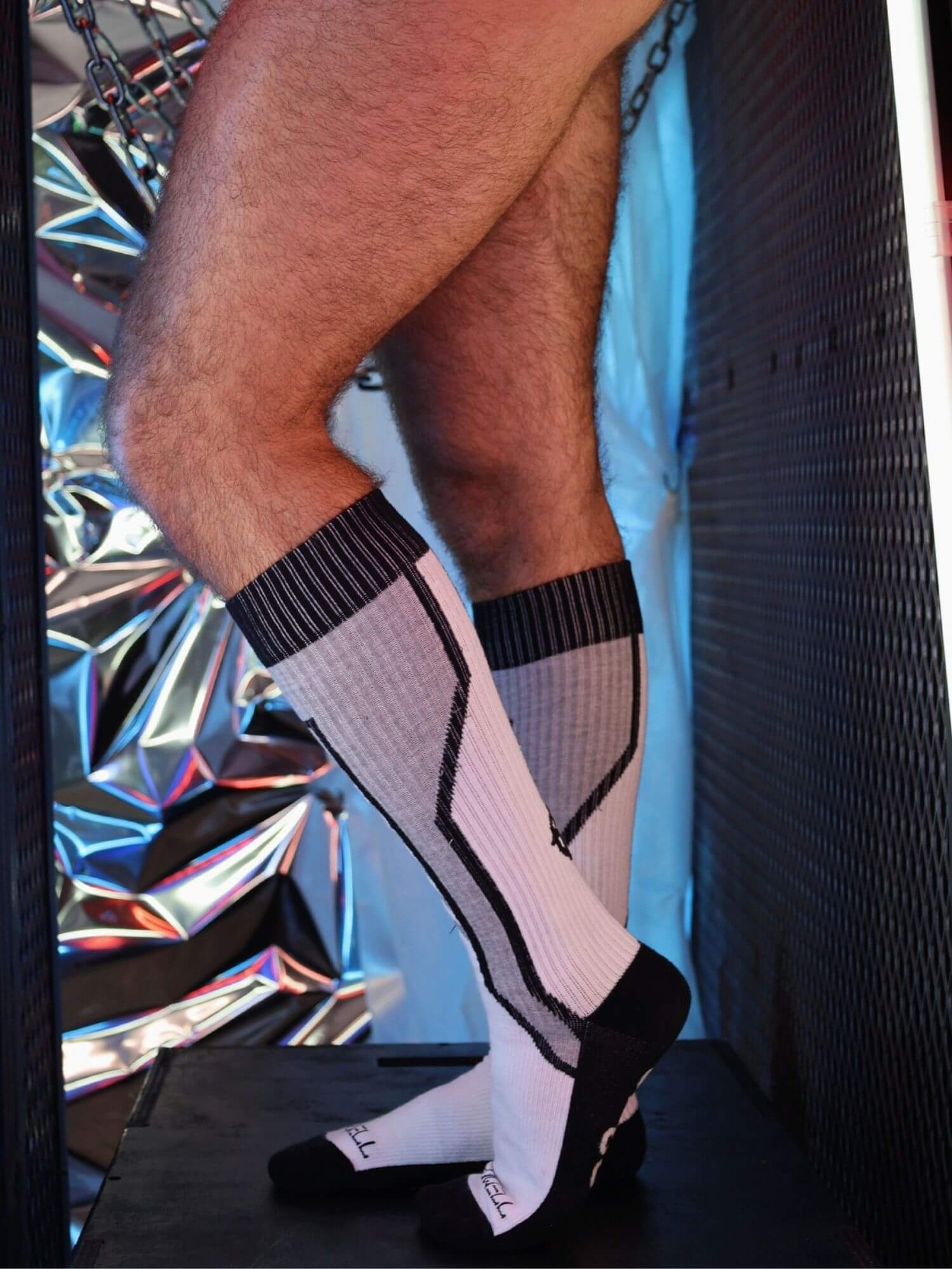 Person wearing grey knee-high socks with a colorful background