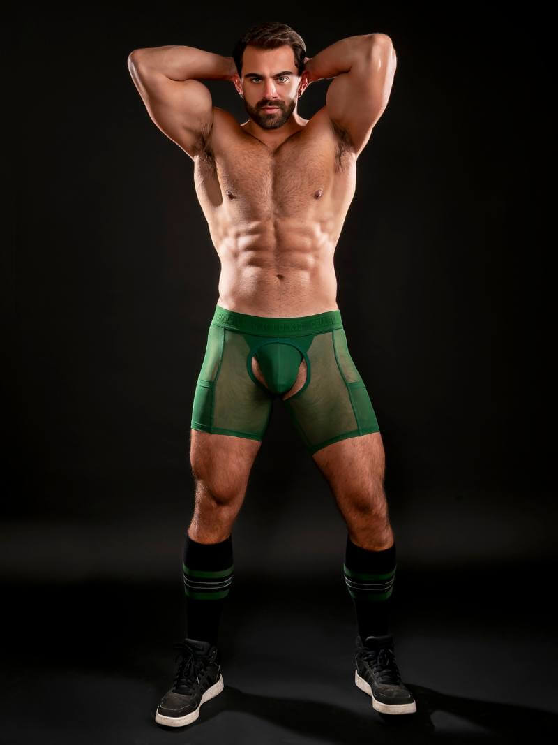 Man wearing green underwear against a black background
