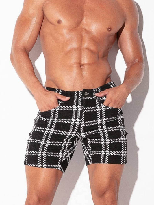 Man wearing black and white checkered shorts on a plain background
