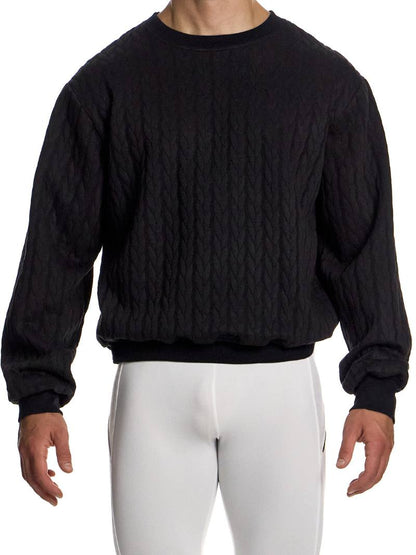 Person wearing a black cable knit sweater and white pants on a white background