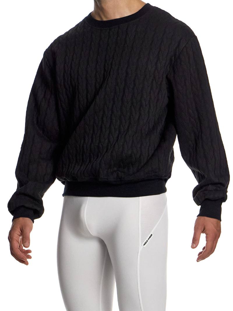 Person wearing a black textured sweater and white leggings on a white background