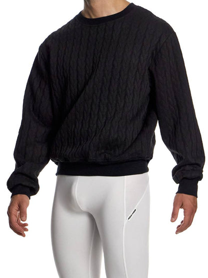 Person wearing a black textured sweater and white leggings on a white background