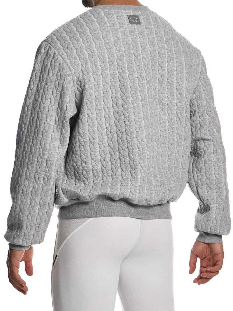 Person wearing a textured gray sweater and white pants on a white background