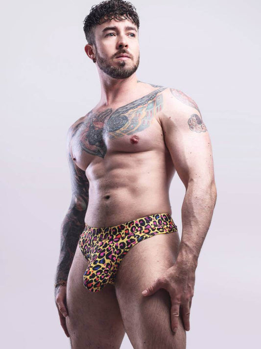 Man wearing colorful leopard print underwear against a plain background