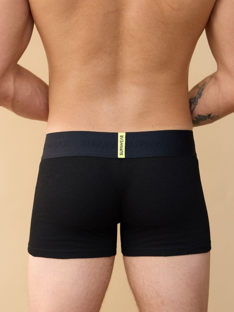 Black boxer briefs with a visible brand logo on a beige background