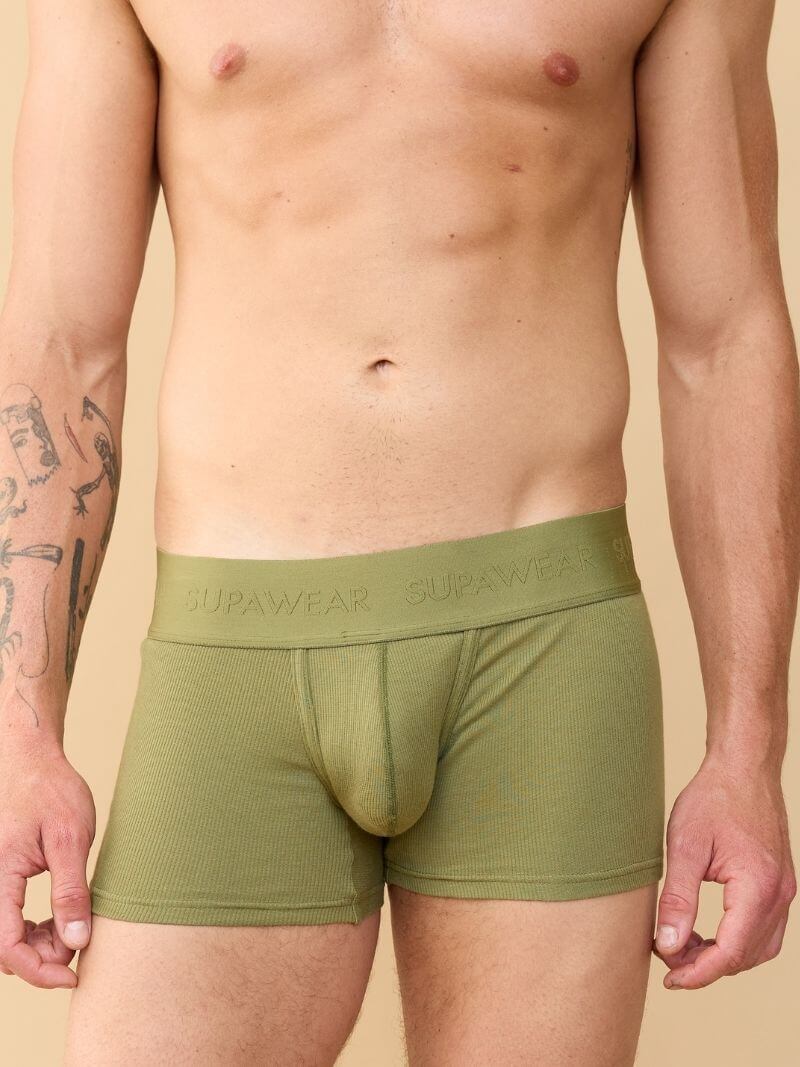 Person wearing green boxer briefs with 'Supawear' branding on a beige background