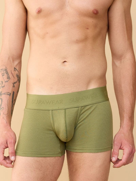 Person wearing green boxer briefs with 'Supawear' branding on a beige background