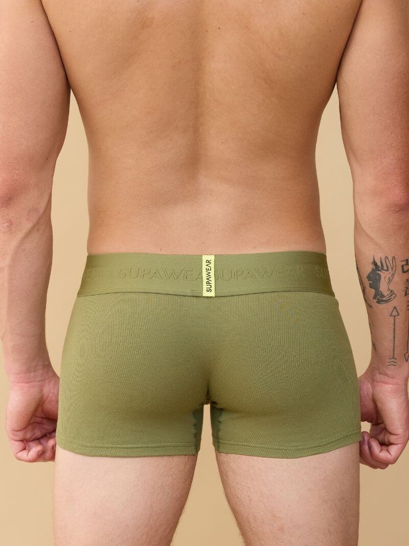 Person wearing green boxer briefs with a beige background
